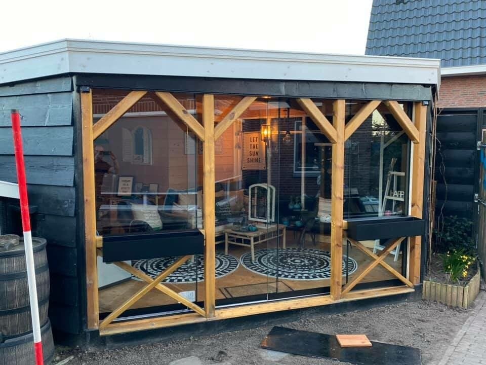 Zwart stalen frame met houten kruisschoren en glazen schuifwanden
